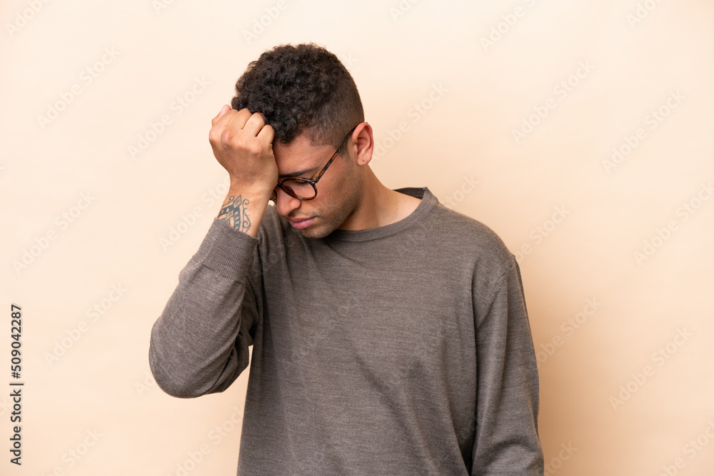 Young Brazilian man isolated on beige background with headache Young Brazilian man isolated on beige background with headache