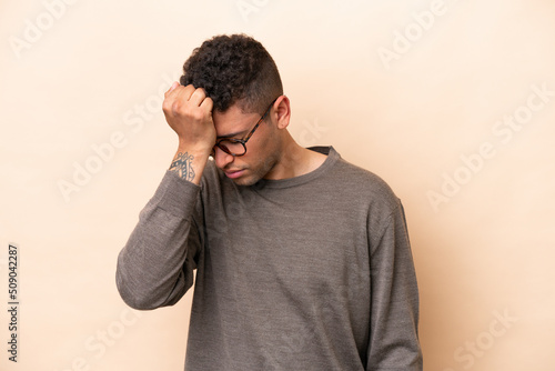 Young Brazilian man isolated on beige background with headache