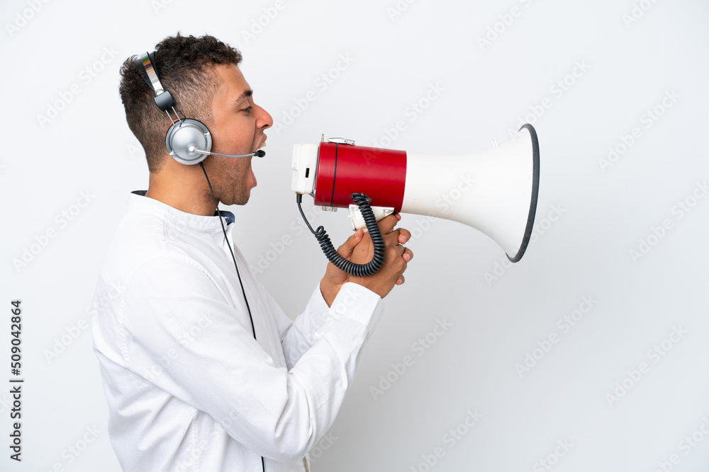 Telemarketer Brazilian man working with a headset isolated on white background shouting through a megaphone Telemarketer Brazilian man working with a headset isolated on white background shouting through a megaphone