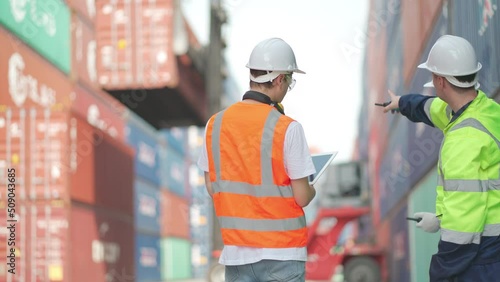Close up back of cargo container engineer or technician use walkie talkie to control their team and one also record the data to support the other one.