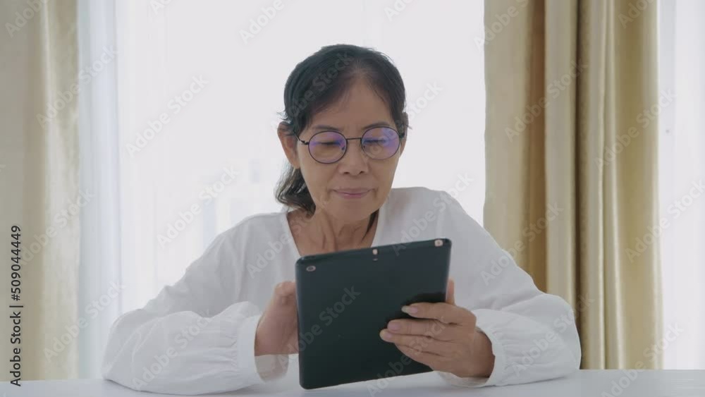 Holiday concept of 4k Resolution. Asian old women are interested in technology and are using tablets in the house. Holiday concept of 4k Resolution. Asian old women are interested in technology and are using tablets in the house.