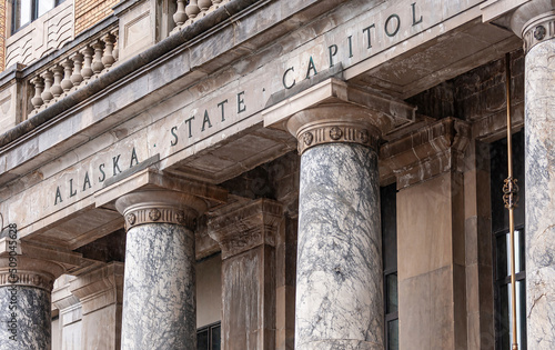 Juneau, Alaska, USA - July 19, 2011: Closeup, Frieze of Alaska State Capitol, stating as much, on top of marble pillars. Brown stone building.