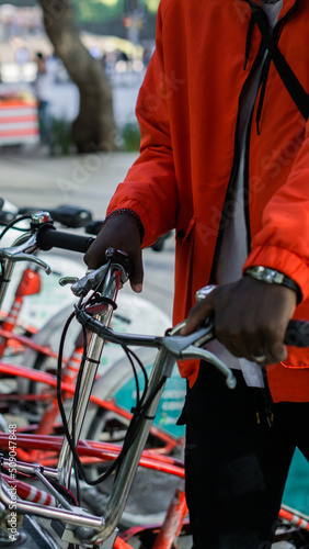 Close up of an African man riding a bicycle in a park outside.