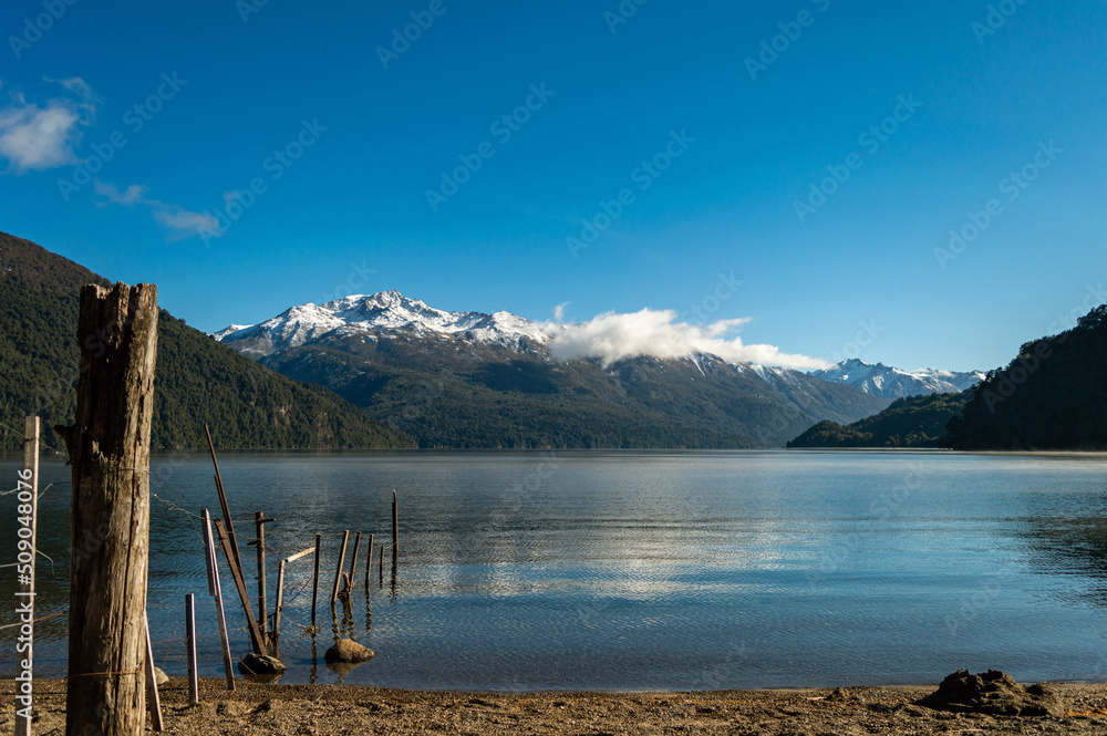 Woods of an old pier with a snowy mountain range in the background. Rivadavia Lake, Los Alerces National Park