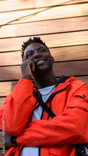 Fényképezés African man smiling and with an amused expression wearing a red jacket
