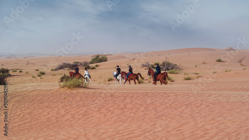 Horseback riding in the desert. Beautiful wavy sands, dunes and riders on horseback.