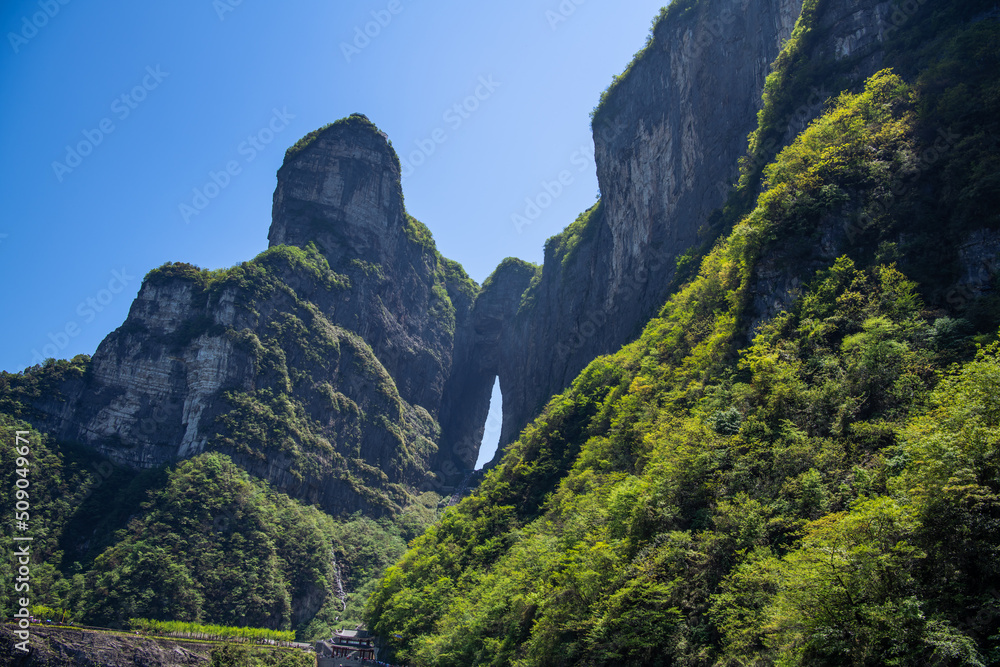 Obraz premium Horizontal wallpaper shot of the Tianmen cave covered with green forest in Zhangjiajie, Hunan, China, copy space for text