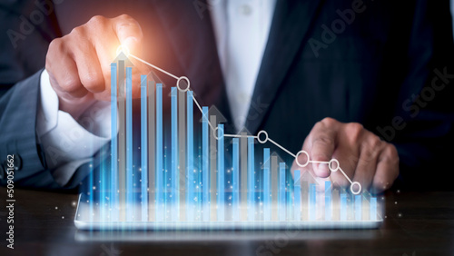 Businessman hand using tablet with creative glowing arrow and stock chart. Hand of businessman use tablet analysis stock market graph growth and increase of chart positive indicators.