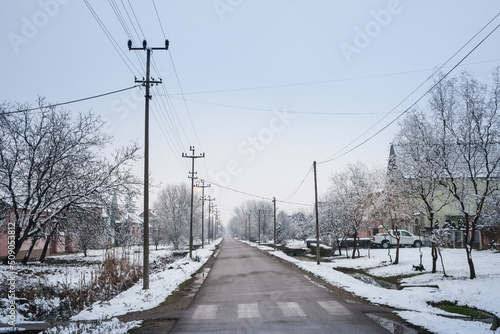 Selective blur on an empty road and street in the village of Bavaniste, in Vojvodina, Banat, Serbia, in the countryside, covered in snow, during a cold freezing afternoon of winter. ..