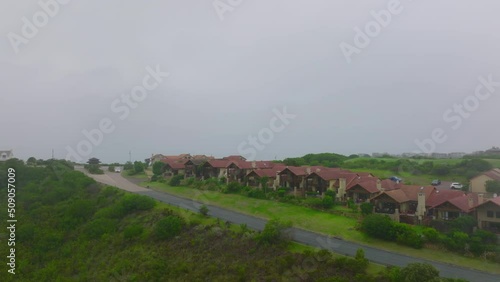 Group of similar family houses along road. Residential complex in suburbs on hazy day. Port Elisabeth, South Africa