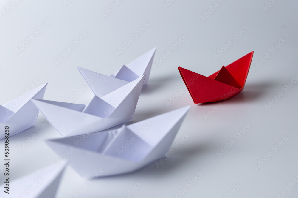 Leadership and teamwork concept, Red paper ship leading among white Leadership and teamwork concept, Red paper ship leading among white