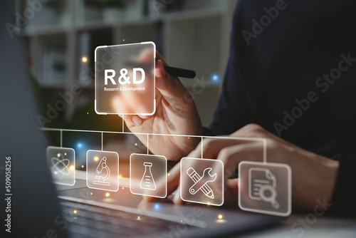Hand of businessman holding a pen pointing to R and D icon for Research and Development on laptop screen. Manage costs more efficiently. R and D innovation concept.