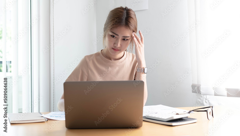 Young Asian woman feeling migraine head strain. Tired, Overworked businesswoman financier while working on laptop computer in office. Young Asian woman feeling migraine head strain. Tired, Overworked businesswoman financier while working on laptop computer in office.