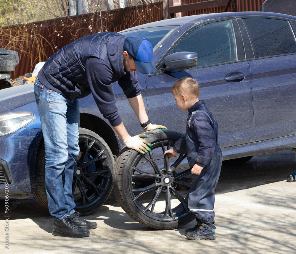 Father and son are fixing the car. The son helps the dad. Happy Father's Day. Father and son are fixing the car. The son helps the dad. Happy Father's Day.