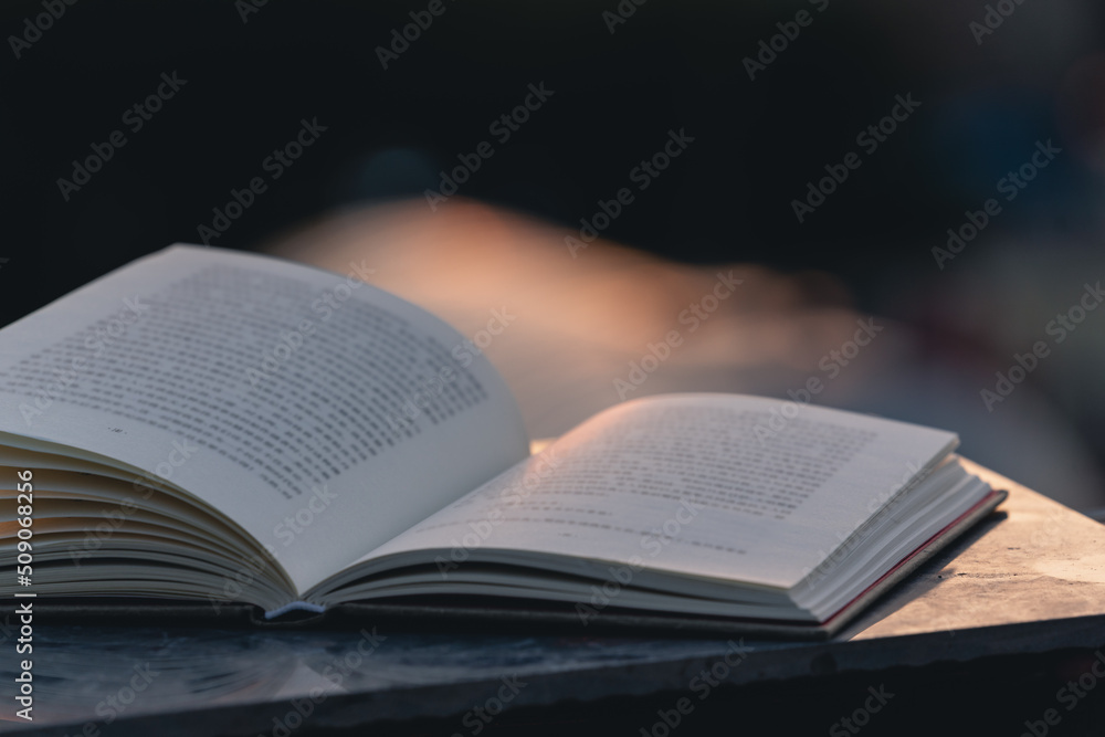 opened book on the table outdoors at sunset time opened book on the table outdoors at sunset time
