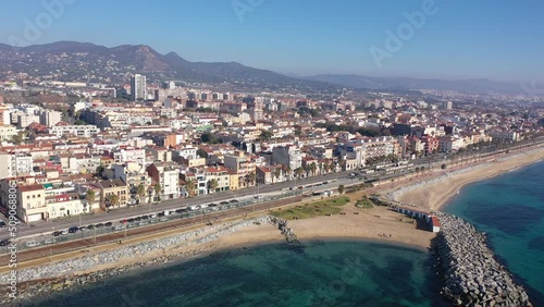 Scenic aerial view of coastal area of Spanish city of Vilassar de Mar overlooking brownish roofs of buildings and sandy seashore on sunny winter day, Catalonia photo