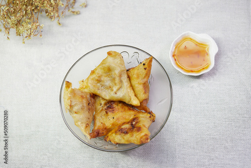 Fried samosa in a glass bowl with sauce photo