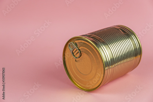 Canned Food. A gold can against a pink background. Selective focus.