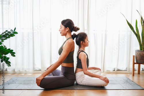 Mother teaching her daughter to yoga pose. New normal lifestyle concept. Healthy lifestyle.