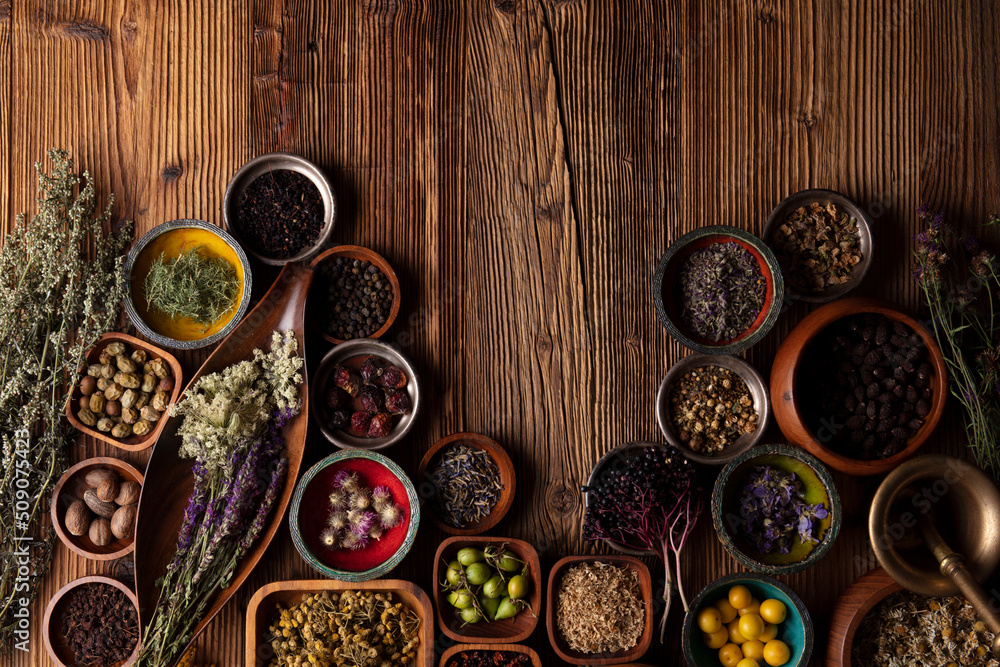 Natural medicine background. Assorted dry herbs in bowls and brass mortar on rustic wooden table. Natural medicine background. Assorted dry herbs in bowls and brass mortar on rustic wooden table.