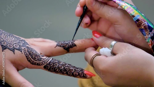 slow motion shot of applying design of hina mehndi on hand big close up photo