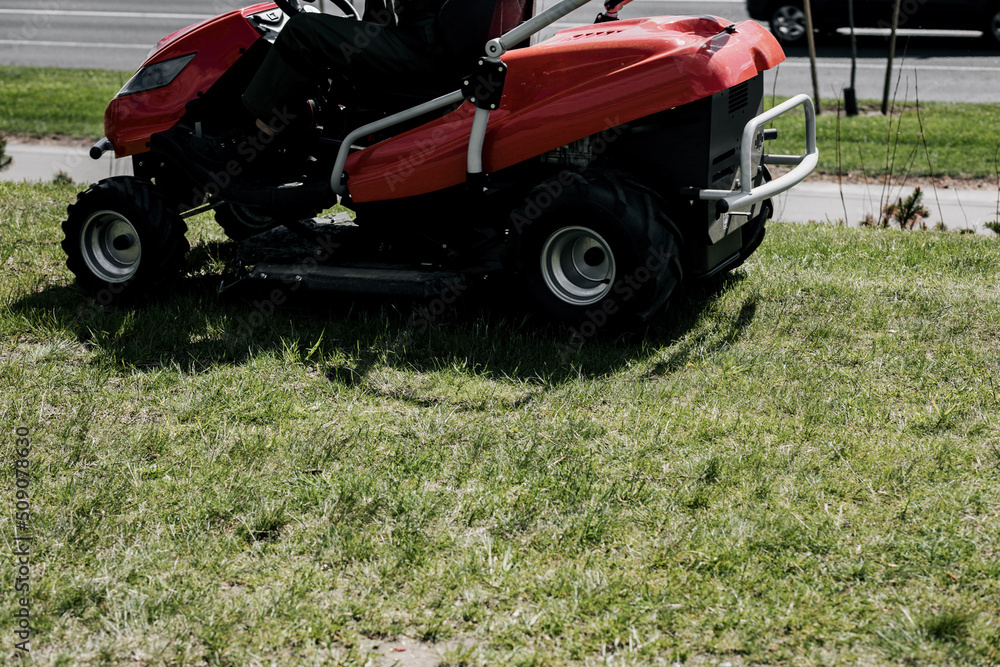 a worker on a lawnmower cuts grass. a worker on a lawnmower cuts grass.