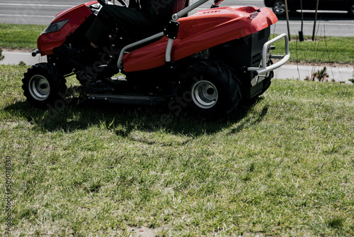 a worker on a lawnmower cuts grass.