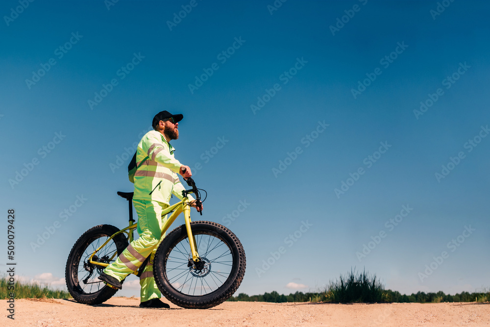 Fat-tire bike in summer driving through the hills. Man is posing with a fat bike in the forest. He performs some tricks and runs dangerously. Bicycle with thick wheels in nature.