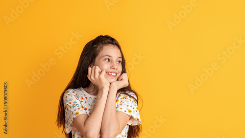 portrait of a pretty attractive cute curious cheerful cheerful girl creating a new idea  fantasizing  copying the space isolated by the yellow background color