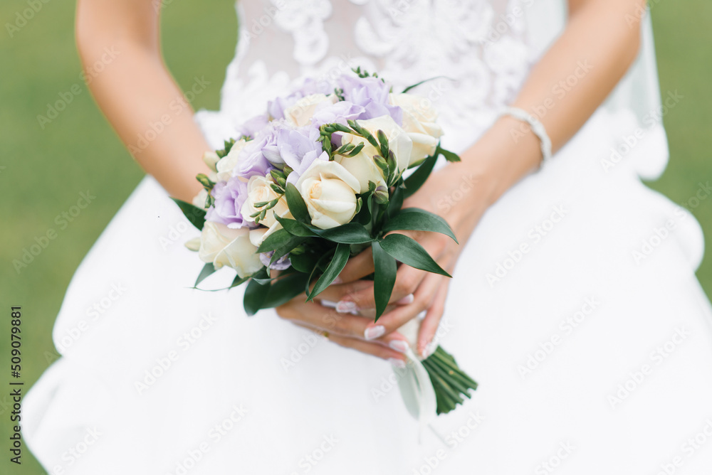 The bride's wedding bouquet of milk roses and lilac eustoms in the hands of the bride The bride's wedding bouquet of milk roses and lilac eustoms in the hands of the bride