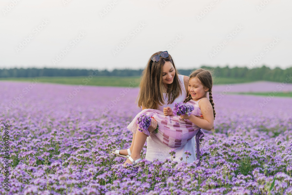 European mother with her six year old daughter having fun in a lilac field on a summer day European mother with her six year old daughter having fun in a lilac field on a summer day