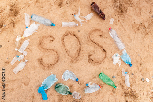 Frame from plastic dirty bottles with text SOS. Top view. The concept of environmental protection and ecology