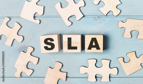 Blank puzzles and wooden cubes with the text SLA Service Level Agreement lie on a light blue background.