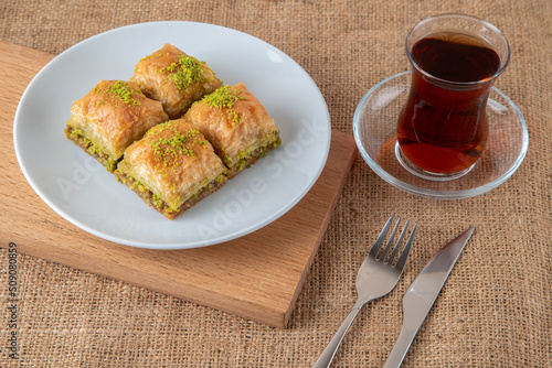 Pistachio baklava on a white plate with Turkish tea	