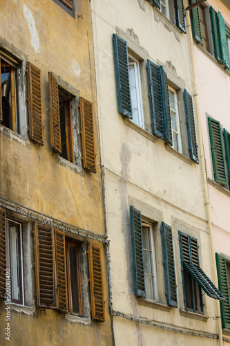 Facade of an old house in Florence with weathered wooden window shutters