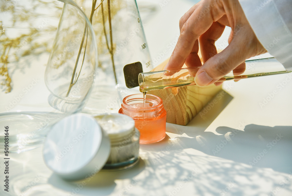 Scientist mixing natural skin care beauty products, Organic botany extraction and scientific laboratory glassware, Blank label cosmetic container for branding mock-up.
