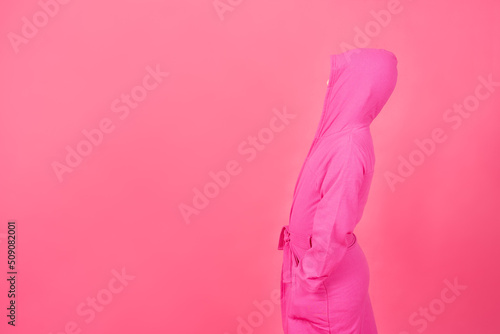 Side view of boy wearing housecoat isolated on pink background. Abstract concept of hiding from problems