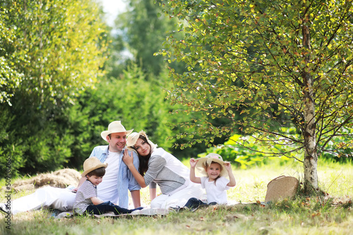 Happy family with children having picnic in park, parents with kids sitting on garden grass and eating watermelon outdoors