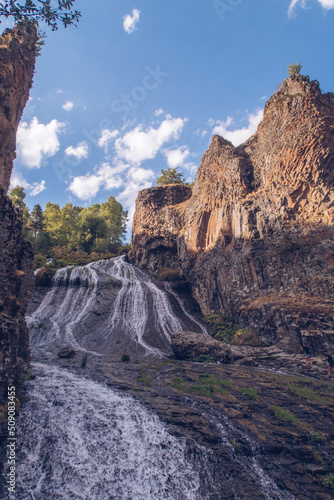 Jermuk waterfall flowing stream picturesque view among the canyon rocks sunlit gorge. Armenian stock photo