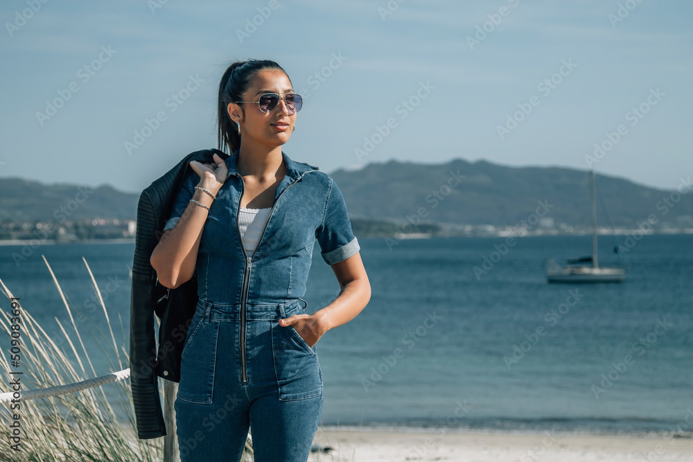 hispanic latin woman walking on the wooden boardwalk of the beach hispanic latin woman walking on the wooden boardwalk of the beach