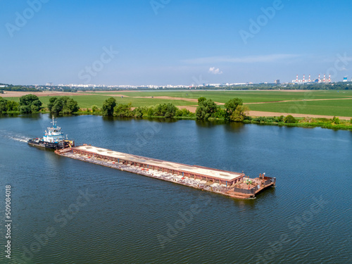 Billede på lærred Towboat transports barge with sand along tranquil river