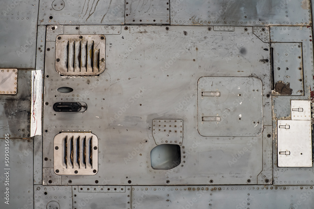 Aluminum surface of the aircraft fuselage. Sheet metal riveted. Aircraft skin close up. Rivets on gray metal.