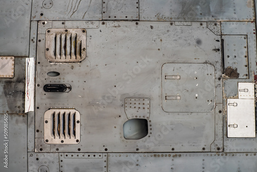Obraz na płótnie Aluminum surface of the aircraft fuselage. Sheet metal riveted. Aircraft skin close up. Rivets on gray metal. w salonie
