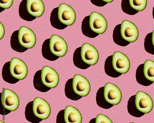 Half a green fresh avocado on a pink background. Healthy vegetable pattern