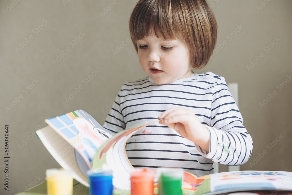 Finger painting. Portrait of cute little boy painting with fingers at home. Close-up of child's hand in colorful paints. Early education concept. Sensory play. Development of fine motor skills. Finger painting. Portrait of cute little boy painting with fingers at home. Close-up of child's hand in colorful paints. Early education concept. Sensory play. Development of fine motor skills.