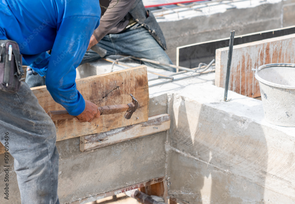 Worker hammering nails on wooden formwork for concrete beam. Worker hammering nails on wooden formwork for concrete beam.