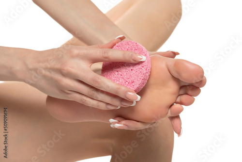 Woman pampring her foot with sponge on a white studio background photo