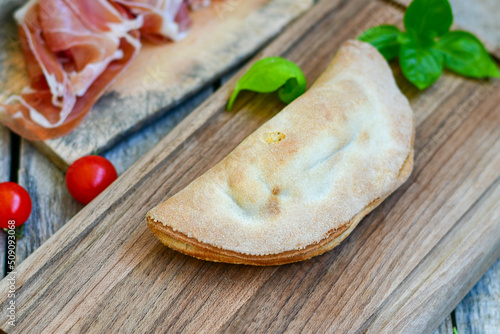 Home made italian calzone pizza with  tomatoes,  prosciutto mozzarella and parmesan cheese and fresh basil 
