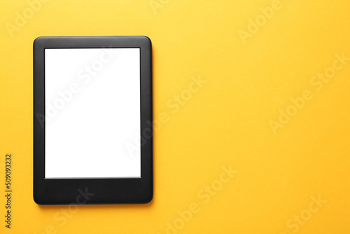 Modern e-book reader with blank screen on orange background, top view. Space for text