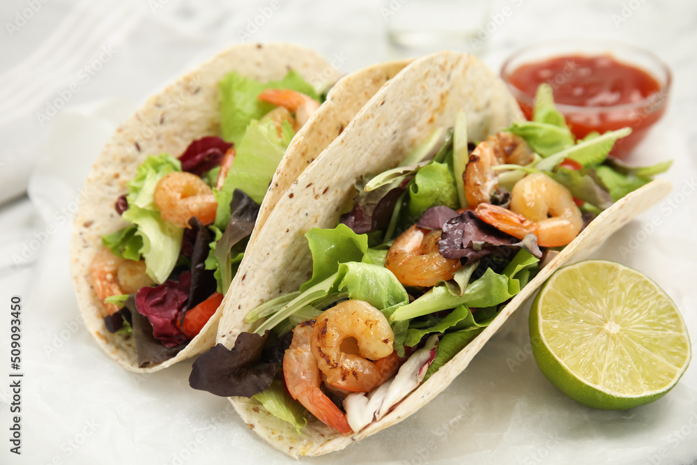 Delicious tacos with shrimps and lime on white table, closeup Delicious tacos with shrimps and lime on white table, closeup